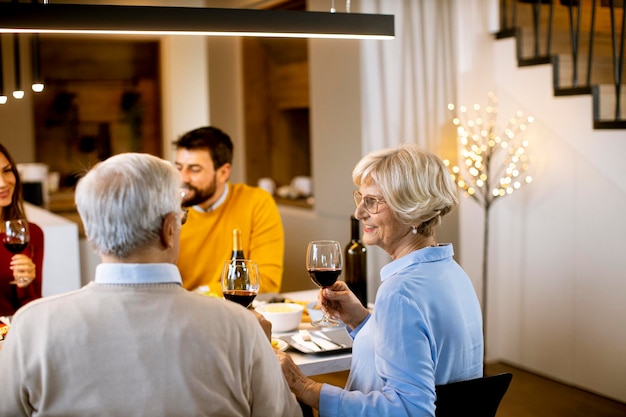 Família feliz jantando com vinho tinto em casa