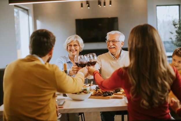 Família feliz jantando com vinho tinto em casa