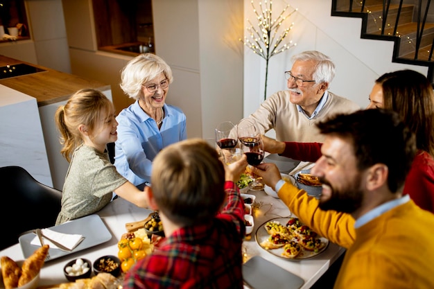 Família feliz jantando com vinho tinto em casa
