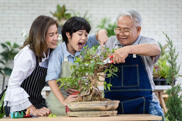 Familia feliz jardinería juntos en el jardín, abuelo nieto y mujer cuidando de la naturaleza