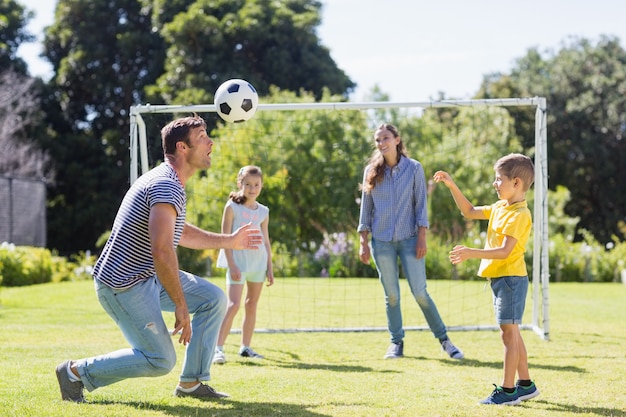 Família feliz jogando futebol no parque