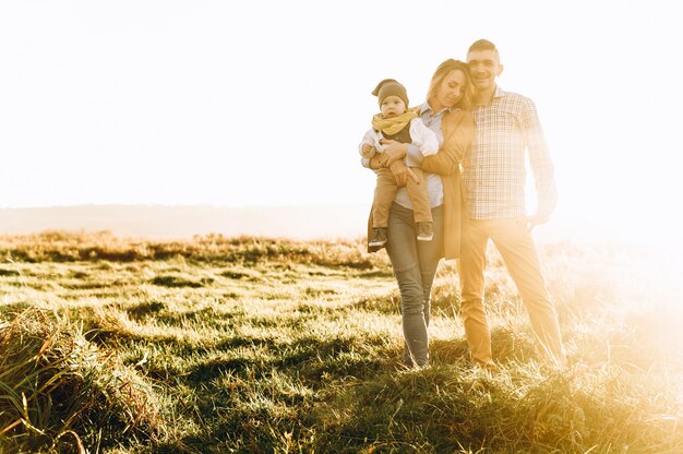 Foto família feliz jogando no campo verde ao pôr do sol