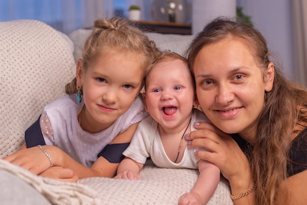 Família feliz, jovem mãe, babá lendo um livro contando às crianças um conto de fadas engraçado sentado