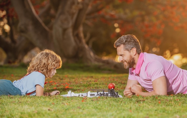 Familia feliz juegos al aire libre y entretenimiento para niños padre e hijo jugando al ajedrez en el jardín de verano