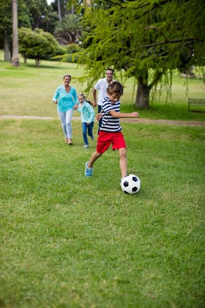 Familia feliz jugando al fútbol en el parque