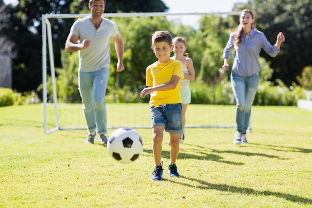 Familia feliz jugando al fútbol en el parque