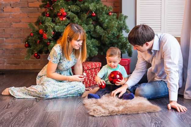 Familia feliz jugando con bolas de Navidad en casa