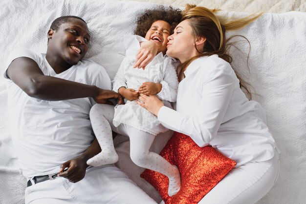 Familia feliz jugando en la cama con su hija