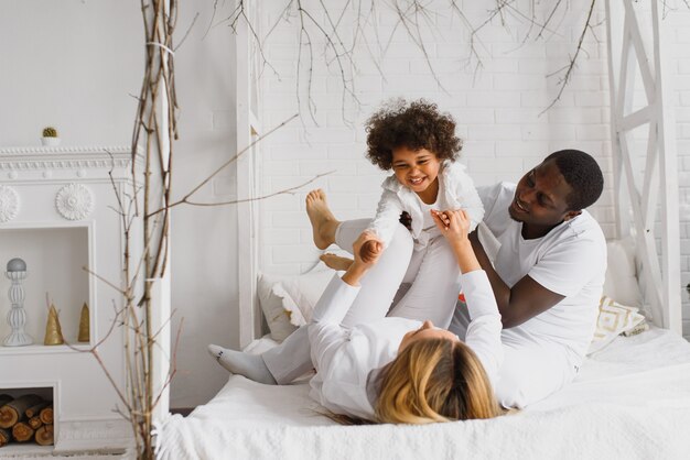 Familia feliz jugando en la cama con su hija