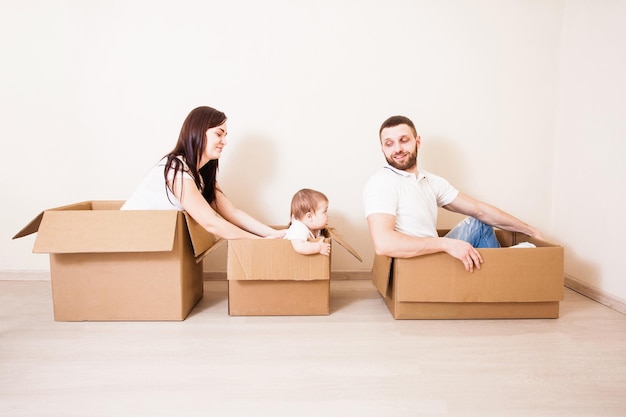 Familia feliz jugando en casa nueva. Padre, madre e hijos divirtiéndose juntos