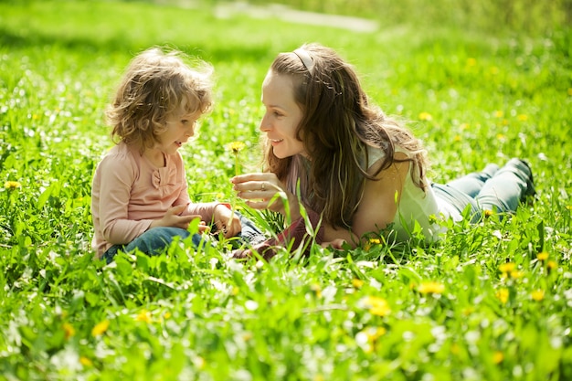 Familia feliz jugando en el excremento verde en el parque de la primavera