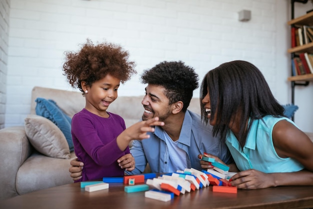 Familia feliz jugando jenga juntos en casa.