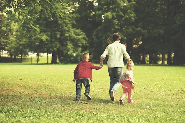 familia feliz jugando juntos al aire libre en el parque madre con niños corriendo sobre el césped