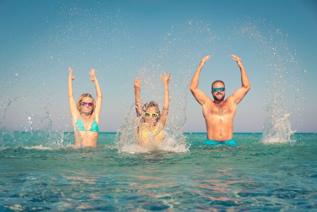 Familia feliz jugando en el mar Niño madre y padre divirtiéndose en las vacaciones de verano Concepto de estilo de vida activo y saludable