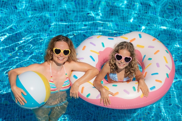 Familia feliz jugando en la piscina al aire libre Gente divirtiéndose en vacaciones de verano Concepto de estilo de vida saludable