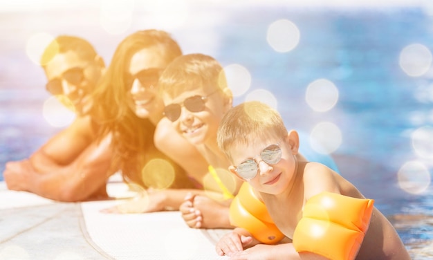 Familia feliz jugando en la piscina. concepto de vacaciones de verano