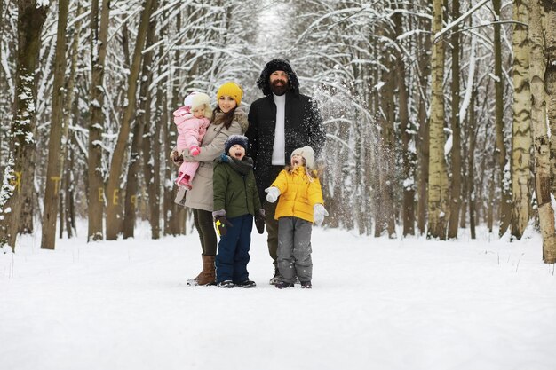 Familia feliz jugando y riendo en invierno al aire libre en el día de invierno del parque de la ciudad de nieve