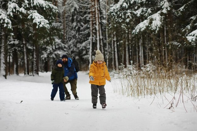 Familia feliz jugando y riendo en invierno al aire libre en el día de invierno del parque de la ciudad de nieve