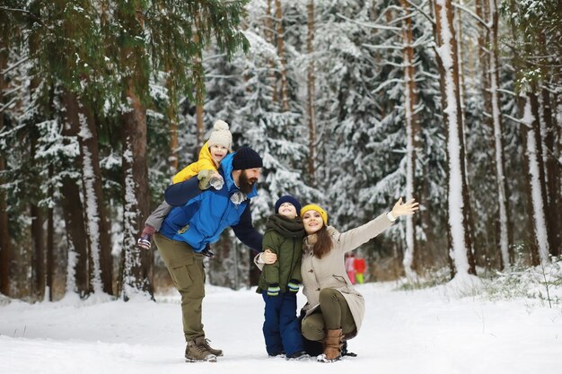 Familia feliz jugando y riendo en invierno al aire libre en la nieve. Parque de la ciudad día de invierno.