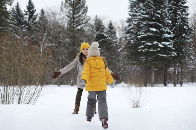 Familia feliz jugando y riendo en invierno al aire libre en la nieve. Parque de la ciudad día de invierno.