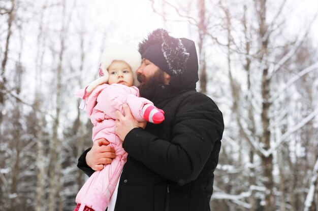 Familia feliz jugando y riendo en invierno al aire libre en la nieve. Parque de la ciudad día de invierno.