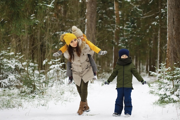 Familia feliz jugando y riendo en invierno al aire libre en la nieve. Parque de la ciudad día de invierno.