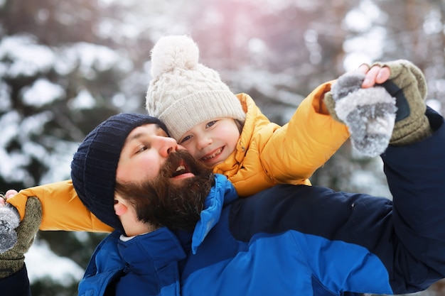 Familia feliz jugando y riendo en invierno al aire libre en la nieve. Parque de la ciudad día de invierno.