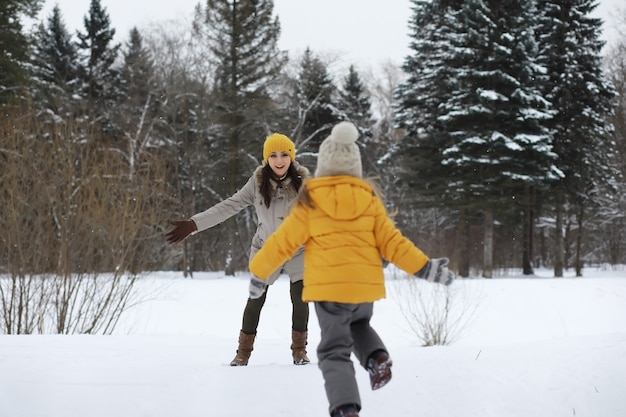 Familia feliz jugando y riendo en invierno al aire libre en la nieve. Parque de la ciudad día de invierno.