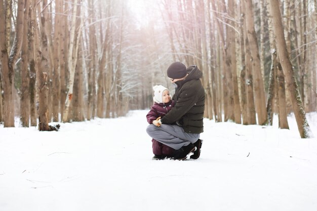 Familia feliz jugando y riendo en invierno al aire libre en la nieve. Parque de la ciudad día de invierno.