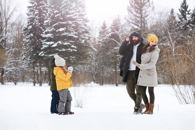 Familia feliz jugando y riendo en invierno al aire libre en la nieve. Parque de la ciudad día de invierno.