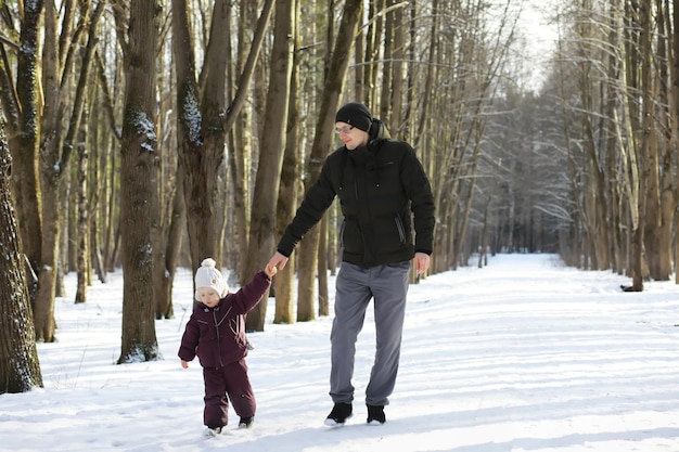 Familia feliz jugando y riendo en invierno al aire libre en la nieve. Parque de la ciudad día de invierno.