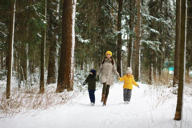 Familia feliz jugando y riendo en invierno al aire libre en la nieve. Parque de la ciudad día de invierno.