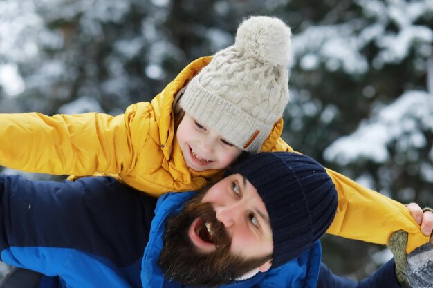 Familia feliz jugando y riendo en invierno al aire libre en la nieve. Parque de la ciudad día de invierno.