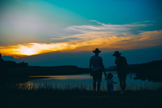 Família feliz juntos, pais com seu filho pequeno ao pôr do sol. Pai levantando o bebê no ar.