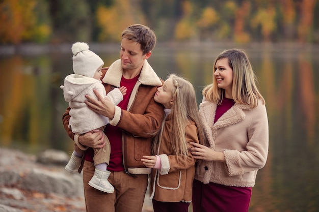 Familia feliz en el lago en las montañas para dar un paseo en el otoño