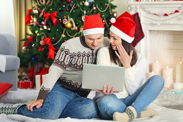 Familia feliz con laptop en árbol de Navidad