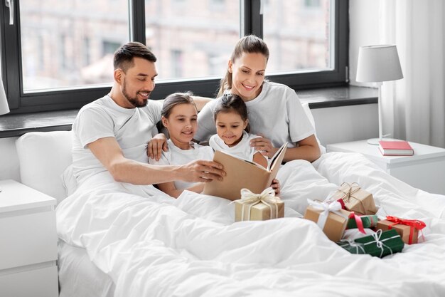família feliz lendo livro na cama no Natal