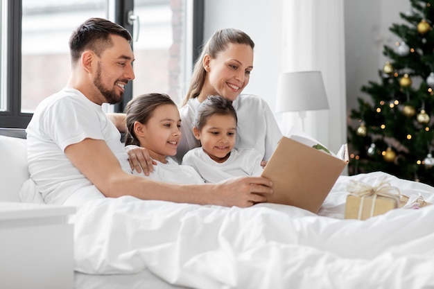 família feliz lendo livro na cama no Natal