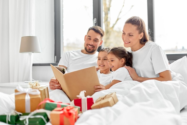 família feliz lendo livro na cama no Natal