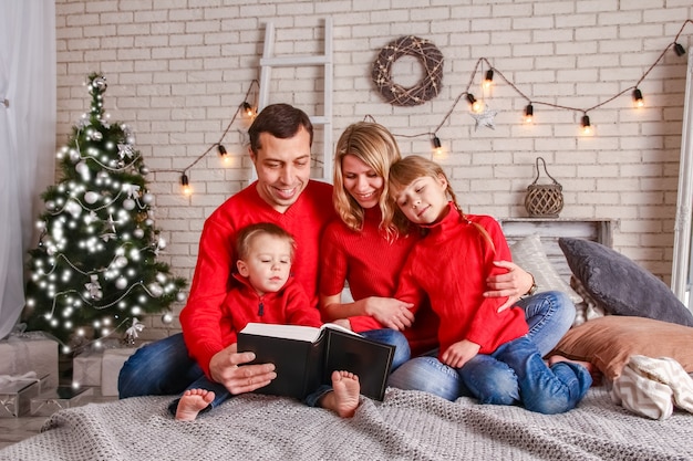 Família feliz lendo um livro em casa no natal