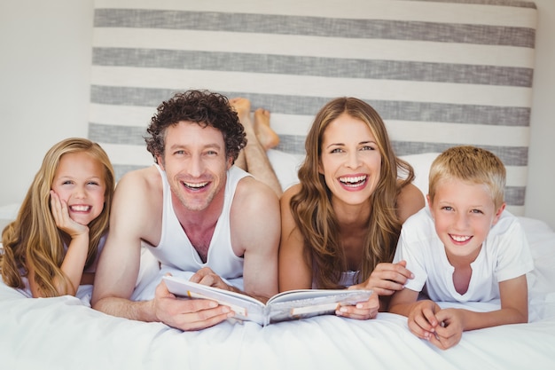 Família feliz, lendo um livro na cama