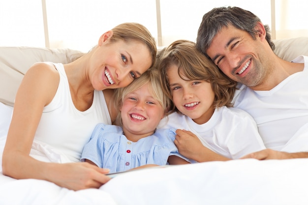 Família feliz lendo um livro na cama