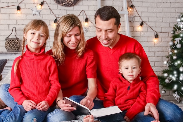 Familia feliz leyendo un libro en casa en Navidad