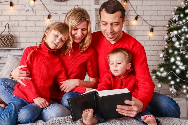 Familia feliz leyendo un libro en casa en Navidad