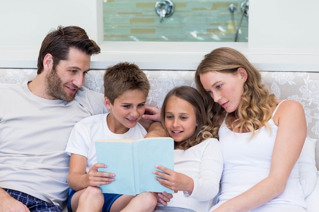 Foto familia feliz en el libro de lectura de la cama