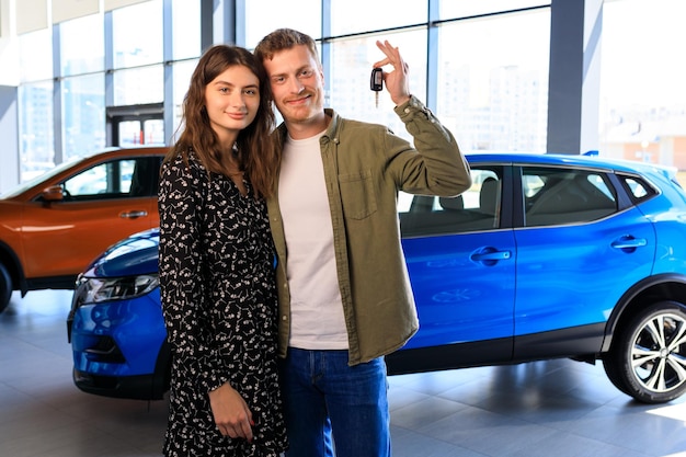 Una familia feliz con la llave de un auto nuevo en el fondo de un concesionario