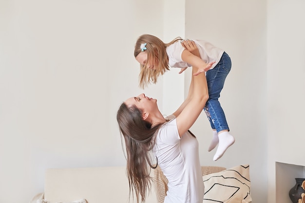 Familia feliz. Madre e hija en casa. Mujer joven y niña. Día de la madre y el niño. Buenos días y concepto de amor. Interior de casa ligero.