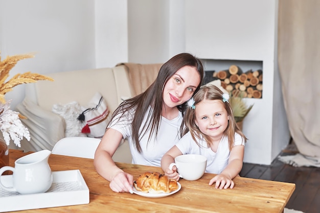 Foto familia feliz. madre e hija en la cocina. mujer joven y niña en casa. día de la madre y el niño. buenos días y concepto de desayuno.