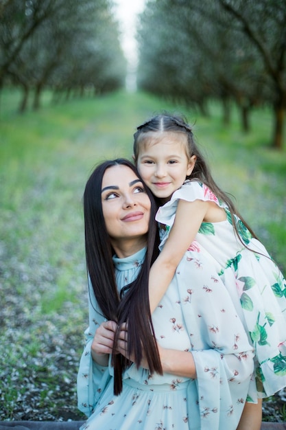 Una familia feliz madre e hija descansan en el parque con vestidos