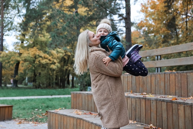 Familia feliz madre e hija están en el parque de la ciudad de otoño Posan sonriendo jugando y divirtiéndose Árboles amarillos brillantes